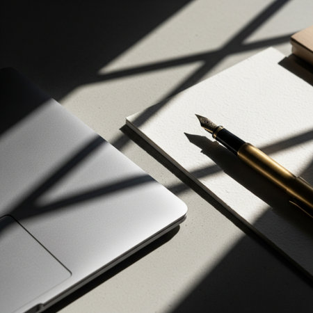 Laptop, pen and notepad on white table with sunlight.の素材