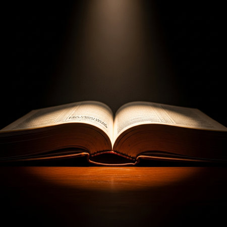 Open book on a wooden table, illuminated by a beam of lightの素材