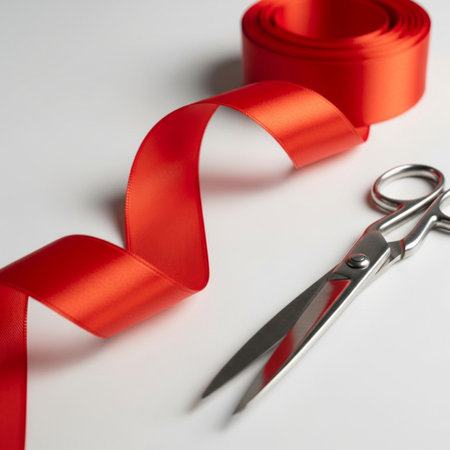 Red ribbon and scissors on a white background, close-up.の素材