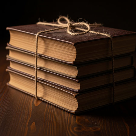 Stack of old books tied with twine on dark wooden background.の素材
