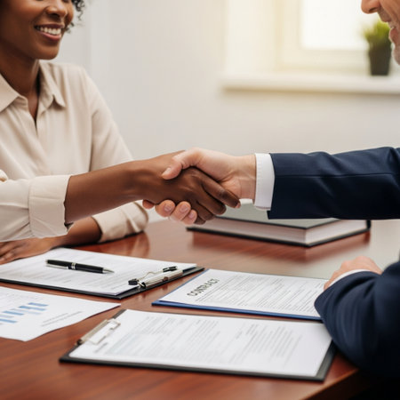 Cropped image of two businesspeople shaking hands while sitting at table in officeの素材