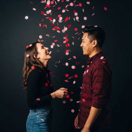 Young asian couple with falling red confetti on black background.の素材