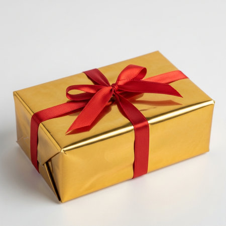 Golden gift box with red ribbon isolated on white background. Christmas or birthday present.の素材