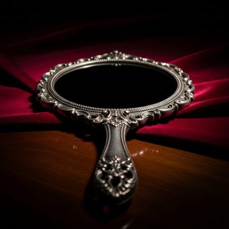 Antique silver hand mirror on red fabric background. Selective focusの素材