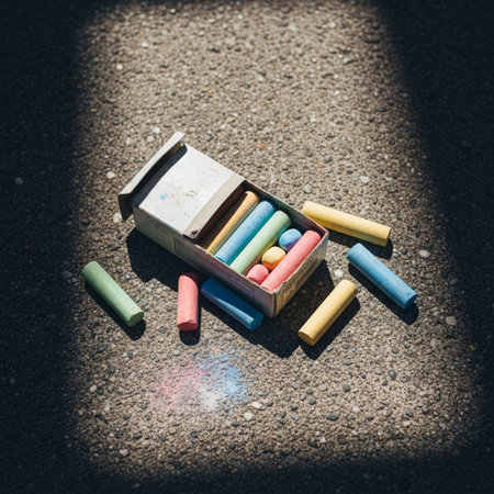 Colorful chalks in a wooden box on the ground with sunlightの素材