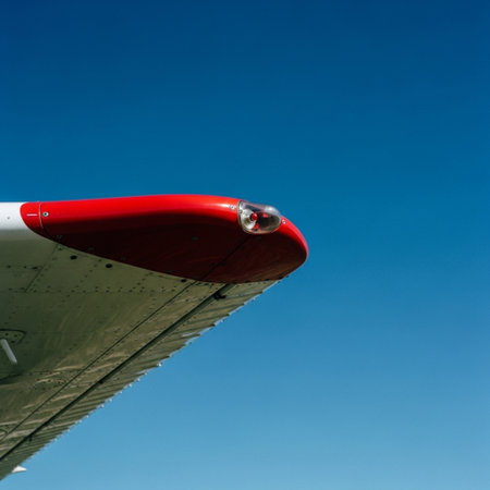 Detail of airplane wing with red propeller against blue sky.の素材