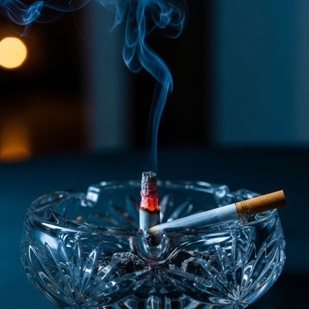 Cigarette in a glass ashtray on a dark backgroundの素材