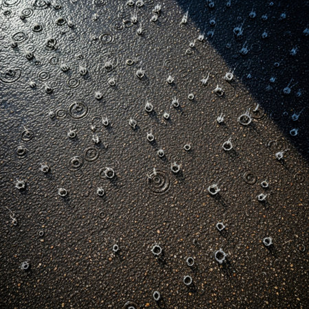 High angle, cinematic view of heavy spring rain hitting dark, gritty asphalt with dramatic reflectioの素材