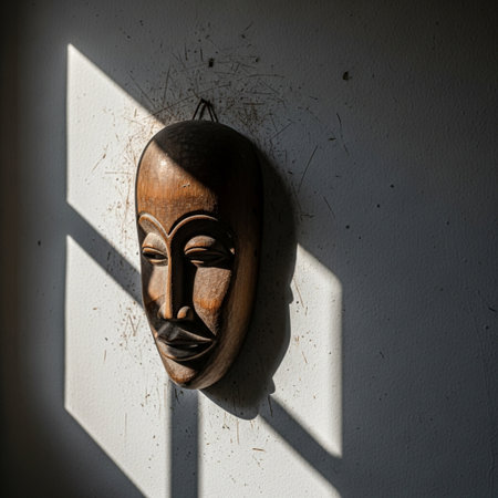 Wooden mask on a white wall with a shadow from a windowの素材