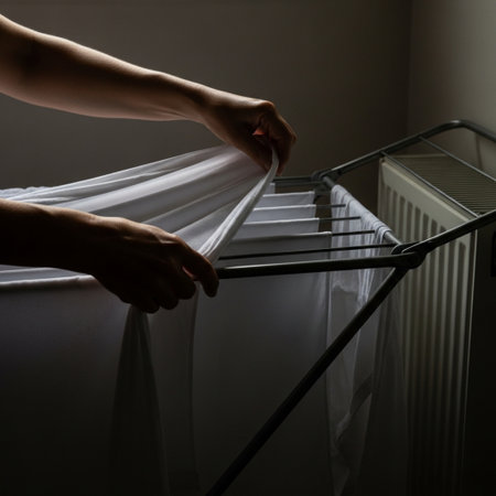 Close-up, editorial image focusing on the careful movement of hands performing a domestic chore. A pの素材