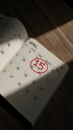 A close-up, cinematic flatlay of a desk calendar with the date April 15th circled prominently in redの素材