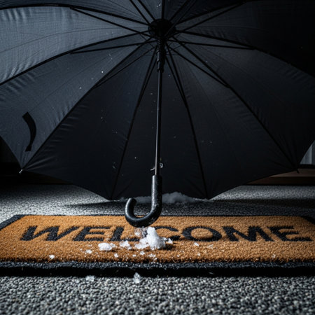 Editorial, low-angle, cinematic photograph of a dark, open umbrella standing centered on a 'Welcome'の素材