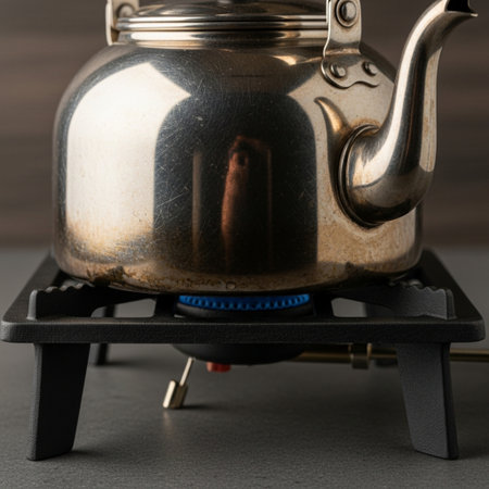 Hero detail shot of an antique silver kettle resting immobile on a portable gas burner, emphasizingの素材