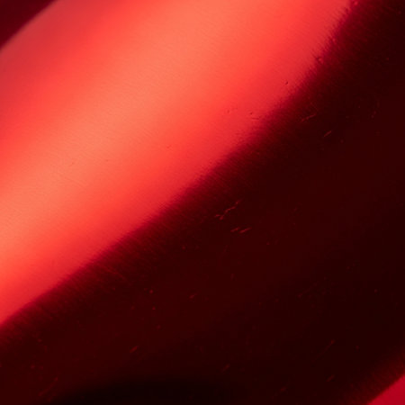 An intimate, hero detail shot of a pristine, but slightly textured, sheet of ruby-red metallic costuの素材