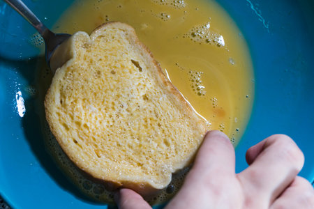 Bread dipped in milk, battered in egg to fry in a pan, for the elaboration of the Torrijas,...