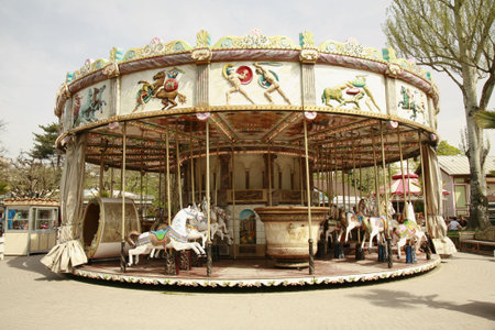 full view of carousel ride , shops and people are behind the carousel 