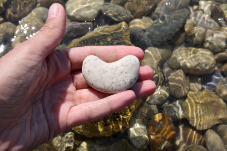 Stone heart in the hand on the beach