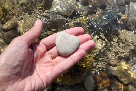 Stone heart in the hand on the beach