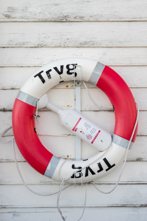 Tryg red lifebuoy on a old grunge wooden plank wallのeditorial素材
