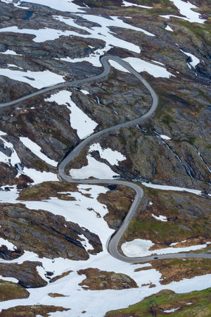 GEIRANGER, NORWAY - 2020 JUNE 21.Curved road on the top of the mountain with snow next to it.の写真素材