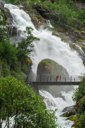 LOEN, NORWAY - 2020 JUNE 20. One person walking on the bridge to Briksdalsbreen Glacier in Norway.のeditorial素材