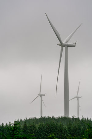 NAERBOE, NORWAY - 2020 JULY 06. Windmills for green electric power production with green trees below.のeditorial素材