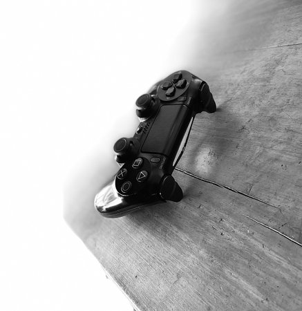 A black and white shot of a gamepad on a wooden surfaceの写真素材
