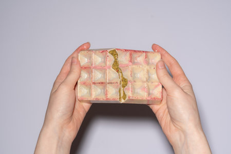 Popular white Dubai chocolate with pistachio, dried raspberry, tahini and kadaif filling, chocolate broken in womans hands. Confectionery and handmade sweets, chocolatierの写真素材