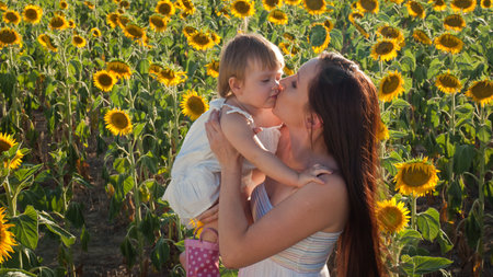 Mother and daughter playing in sunflower field.の写真素材