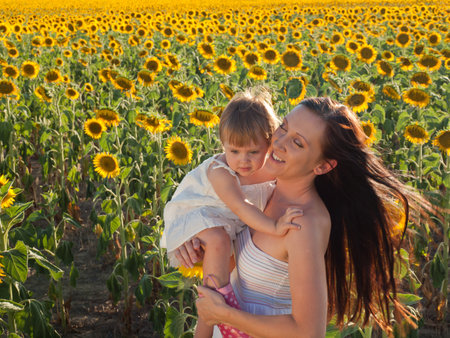 Mother and daughter playing in sunflower field.の写真素材