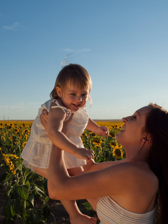 Mother and daughter playing in sunflower field.の写真素材