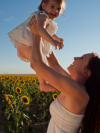 Mother and daughter playing in sunflower field.の写真素材