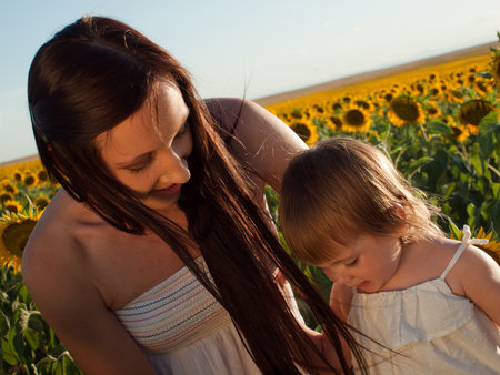 Mother and daughter playing in sunflower field.の写真素材