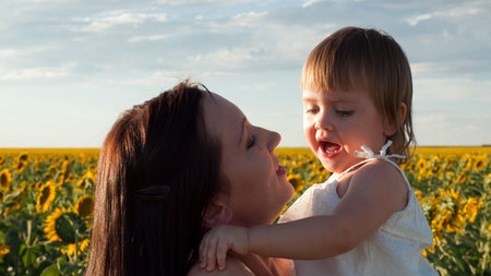 Mother and daughter playing in sunflower field.の写真素材
