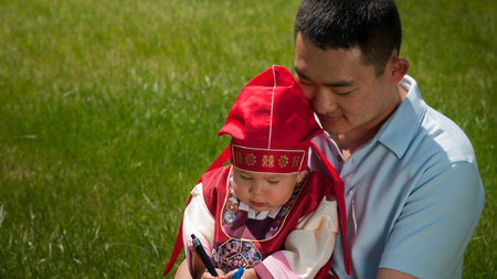 Family celebrating first birthday of their son. Asian baby, one year old child wearing the traditional Korean cultural ethnic attire, called "han-bok".の写真素材