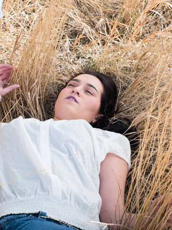 Young woman  laying in field of tall prairie grass.の写真素材