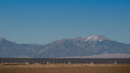 A series of large solar panels forms a symmetrical line at a power plant in the San Luis Valley of central Colorado. These panels utilize a tracking system to follow the sun, collecting its energy and using photovoltaic cells to transform the sunlight intのeditorial素材