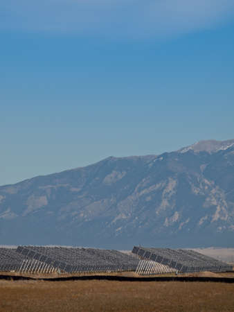 A series of large solar panels forms a symmetrical line at a power plant in the San Luis Valley of central Colorado. These panels utilize a tracking system to follow the sun, collecting its energy and using photovoltaic cells to transform the sunlight intのeditorial素材