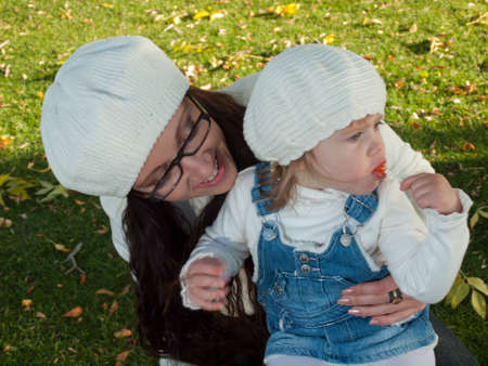 Girl toddler with her mother in autumn park.の写真素材