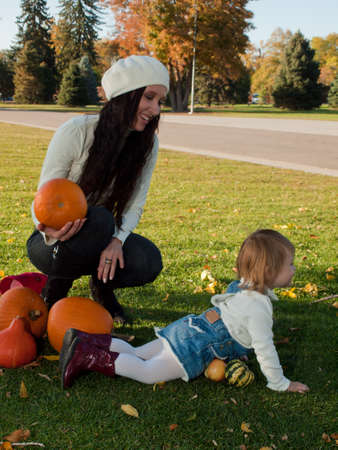 Girl toddler with her mother in autumn park.の写真素材