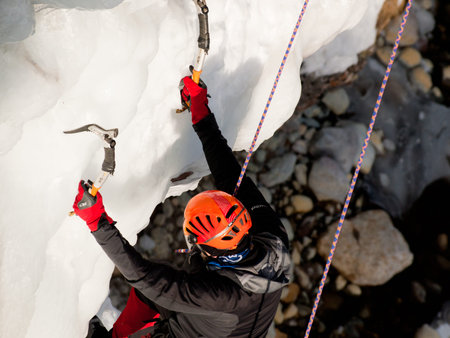 Alpinist ascenting a frozen waterfall in Ice park, Ouray.