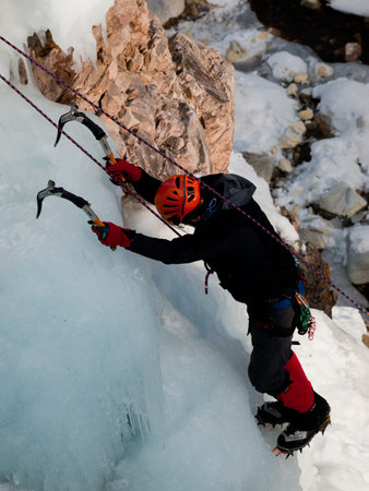 Alpinist ascenting a frozen waterfall in Ice park, Ouray.