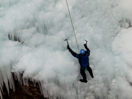 Alpinist ascenting a frozen waterfall in Ice park, Ouray.