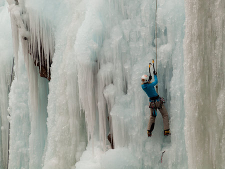 Alpinist ascenting a frozen waterfall in Ice park, Ouray.