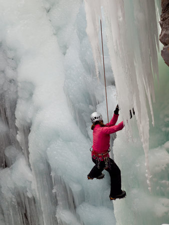 Alpinist ascenting a frozen waterfall in Ice park, Ouray.