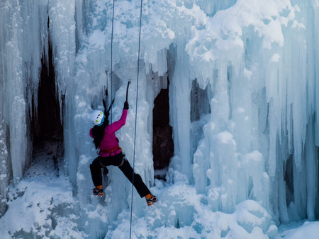 Alpinist ascenting a frozen waterfall in Ice park, Ouray.