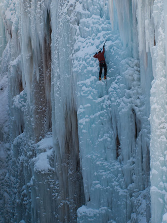 Alpinist ascenting a frozen waterfall in Ice park, Ouray.