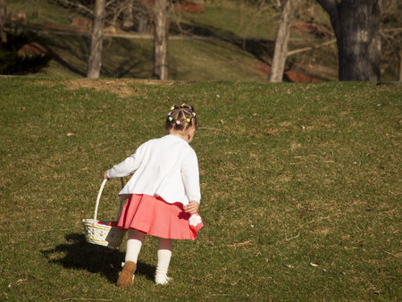 Little toddler girl on Easter egg hunt in urban park.の写真素材