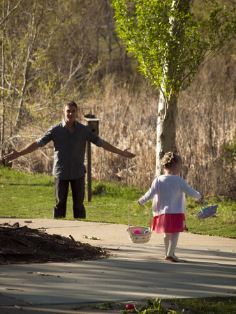 Little toddler girl on Easter egg hunt in urban park.