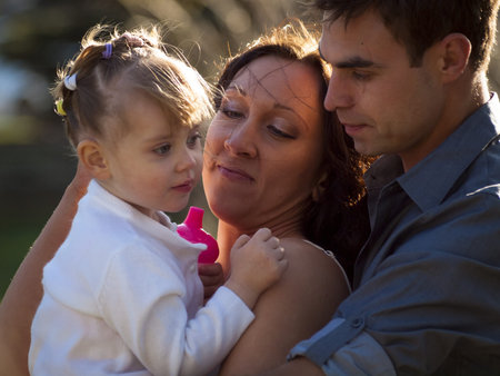 Young family with toddler girl in urban park.